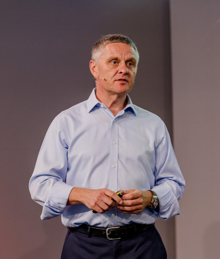 Matthew presenting at a leadership event, wearing a headset and holding a slide clicker.